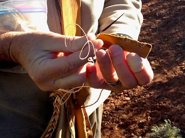 Roy sewing with needle and thread made from yucca plant