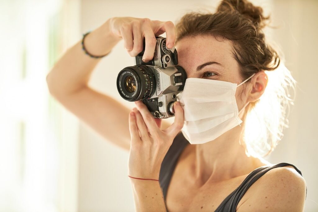 Female photographer with a camera in a mask