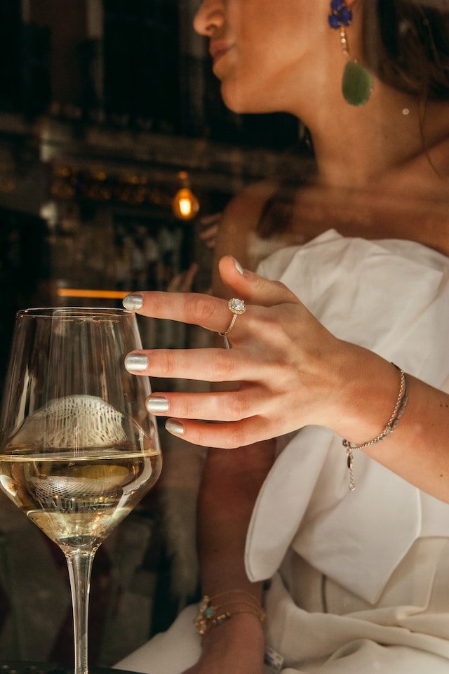 woman drinking wine with diamond ring