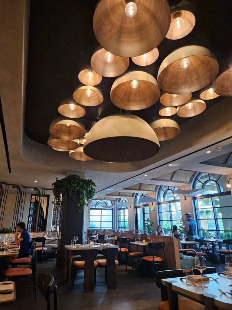 View of dining room of Tia Carmen at the Hyatt Grand. Brass-light fixtures from the ceiling and and showing tables set for dinner.