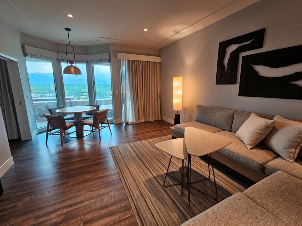 A room in the Grand Hyatt with sofa in foreground and table sitting in front of glass doors.