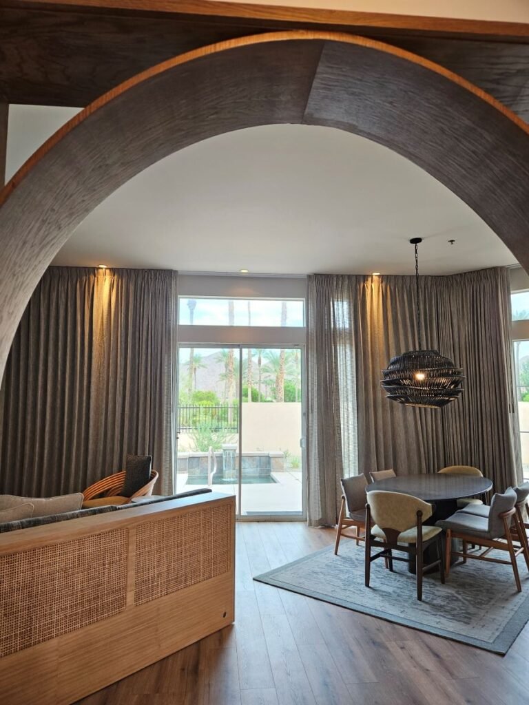 A large arch at the entrance at the entrance of the Hyatt Indian Wells Villa showing sofa and table on the right. With glass sliding doors leading to outsie. 