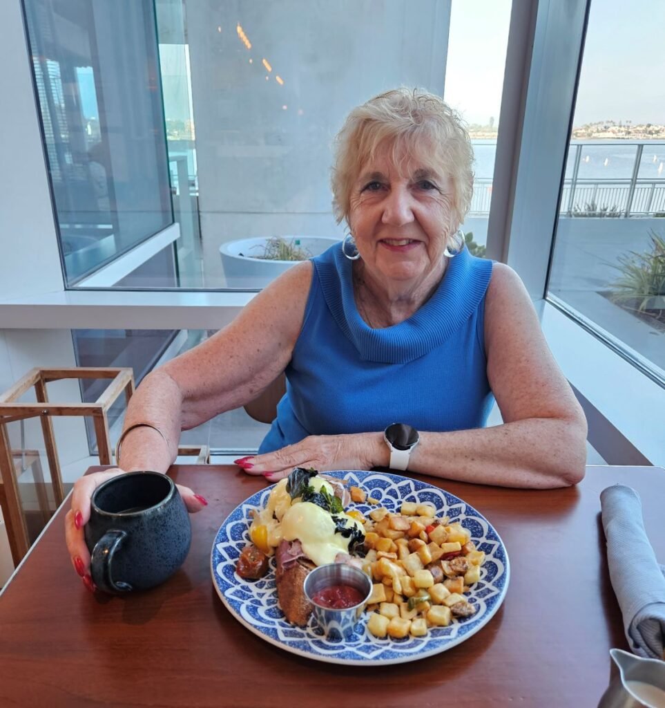 Kathy Condon in blue blouse with a breakfast of eggs benedict at the Hudson and Nash Restaurant