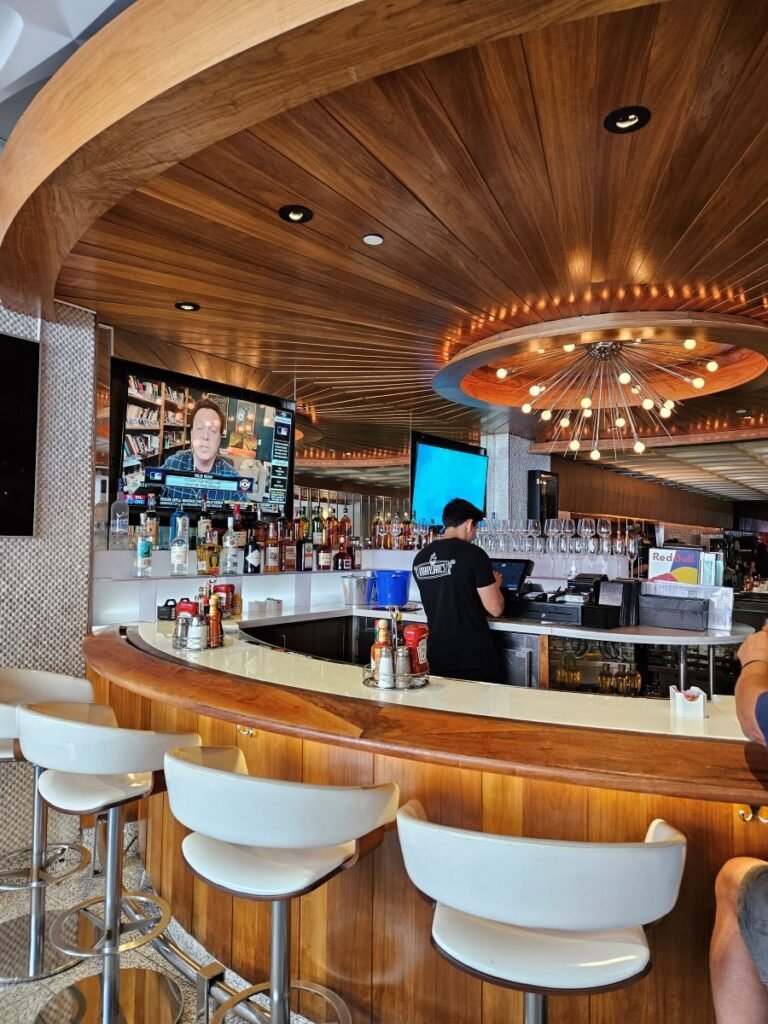 Curve bar with bartender in the background. White bar chairs in the forefront.