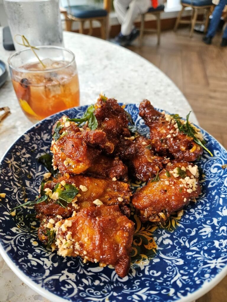 Picture of an Old Fashioned and a plate of chicken wings with chili sauce and spices