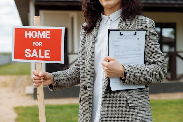 A woman holding a red sign in one hand and a document in the other